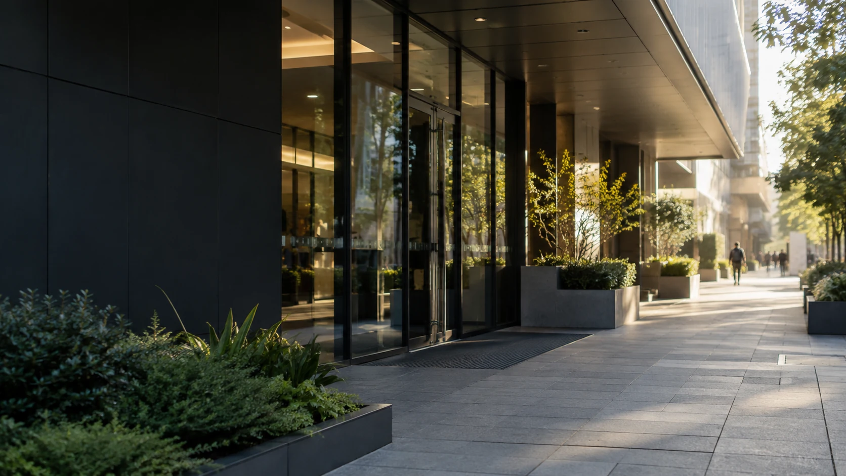 Commercial building entrance and landscaped pedestrian frontage in morning light.
