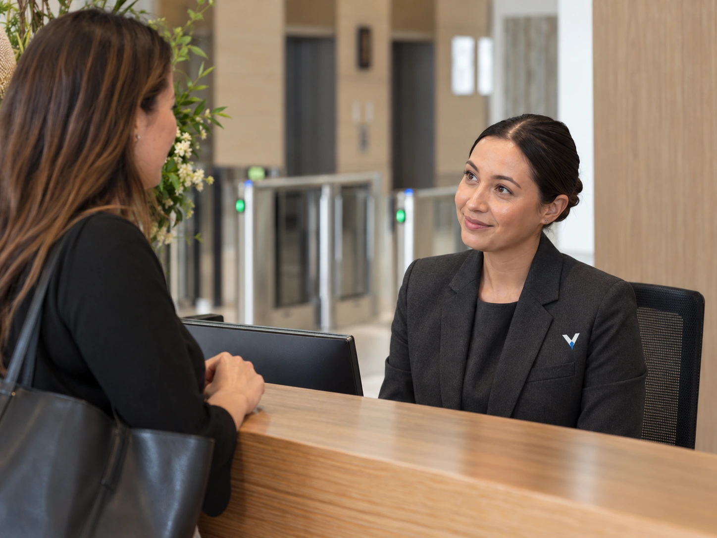 Concierge assisting a visitor beside office access gates.
