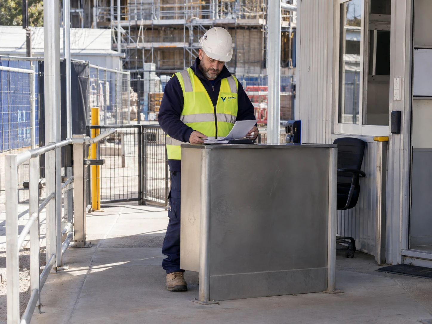 Gatehouse officer reviewing site access records at a construction entrance.